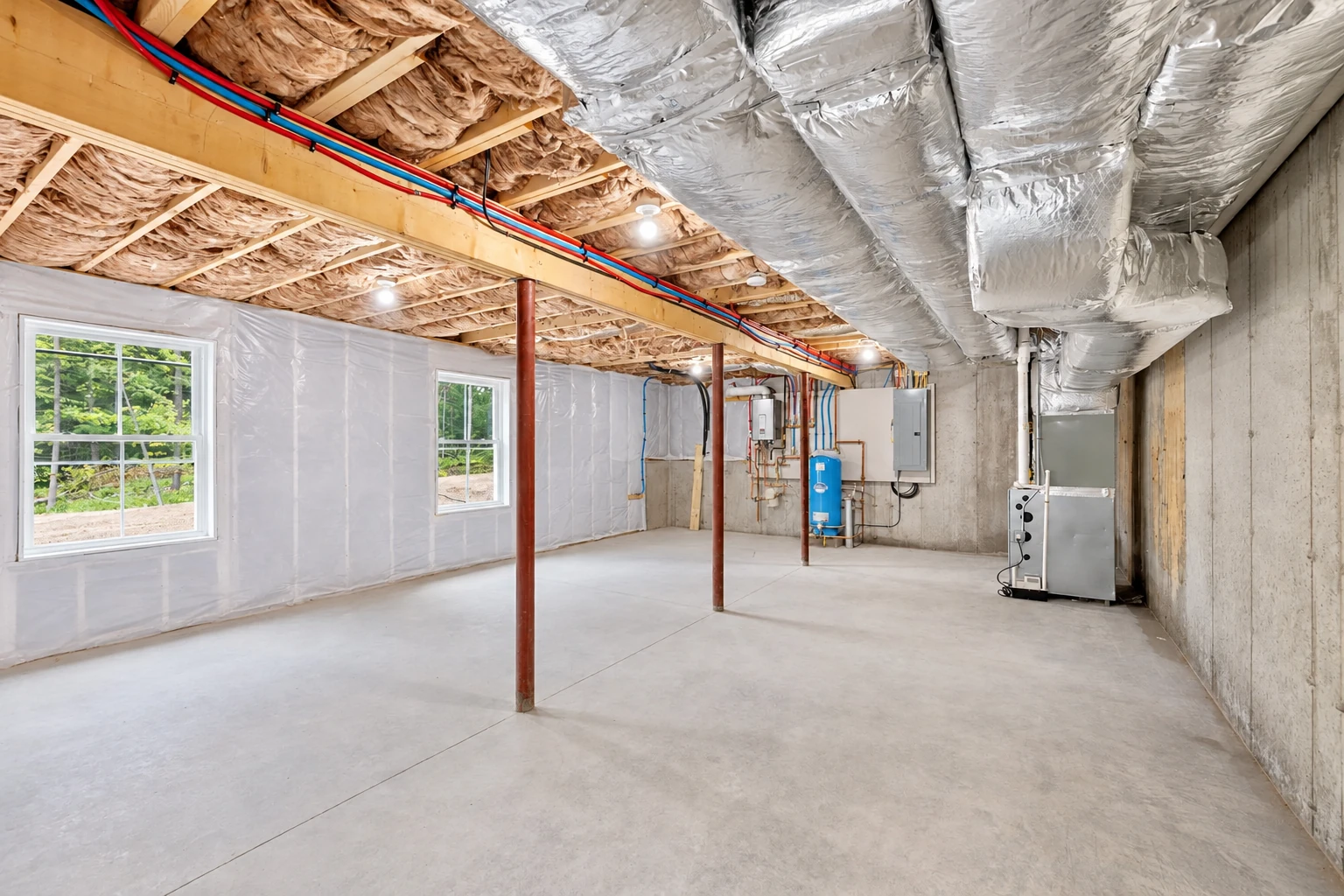 Basement with insulated walls, exposed ceiling joists, ductwork, and utility equipment.